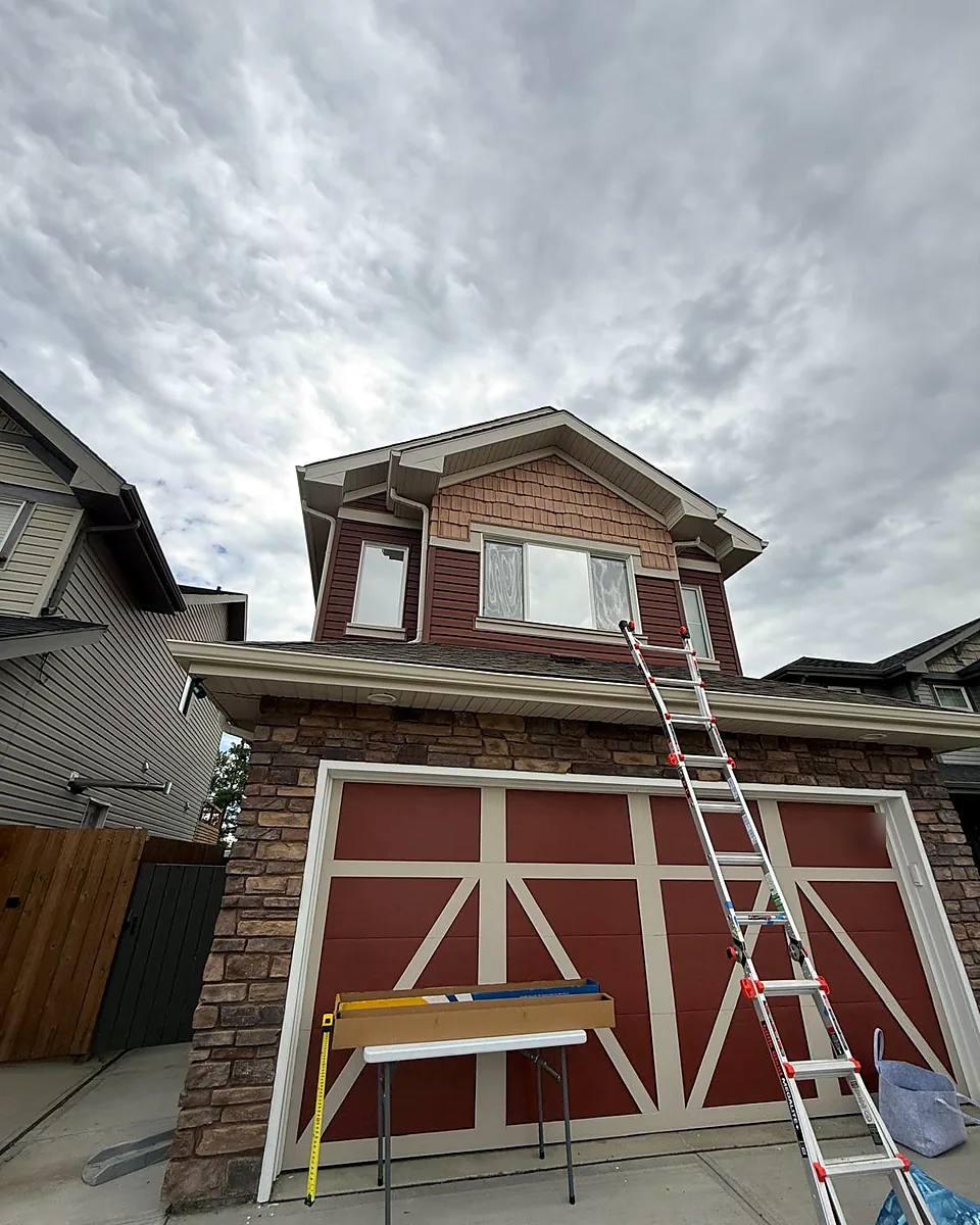 Ladder against a two-story home during a window film installation