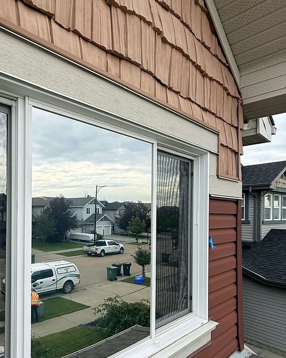 Window with reflective film mirroring the street and houses across the road