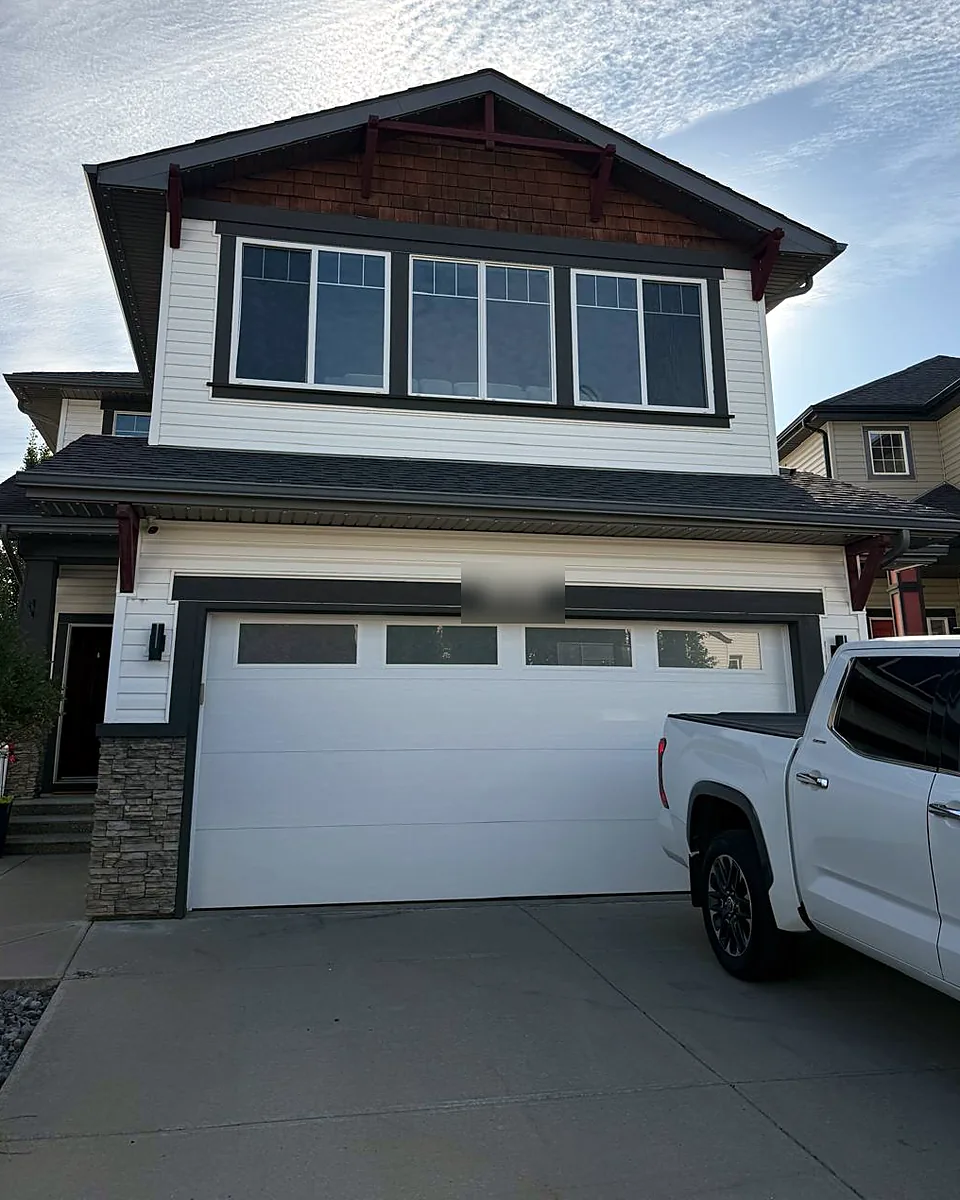 Two-story home with three large tinted windows above a white garage